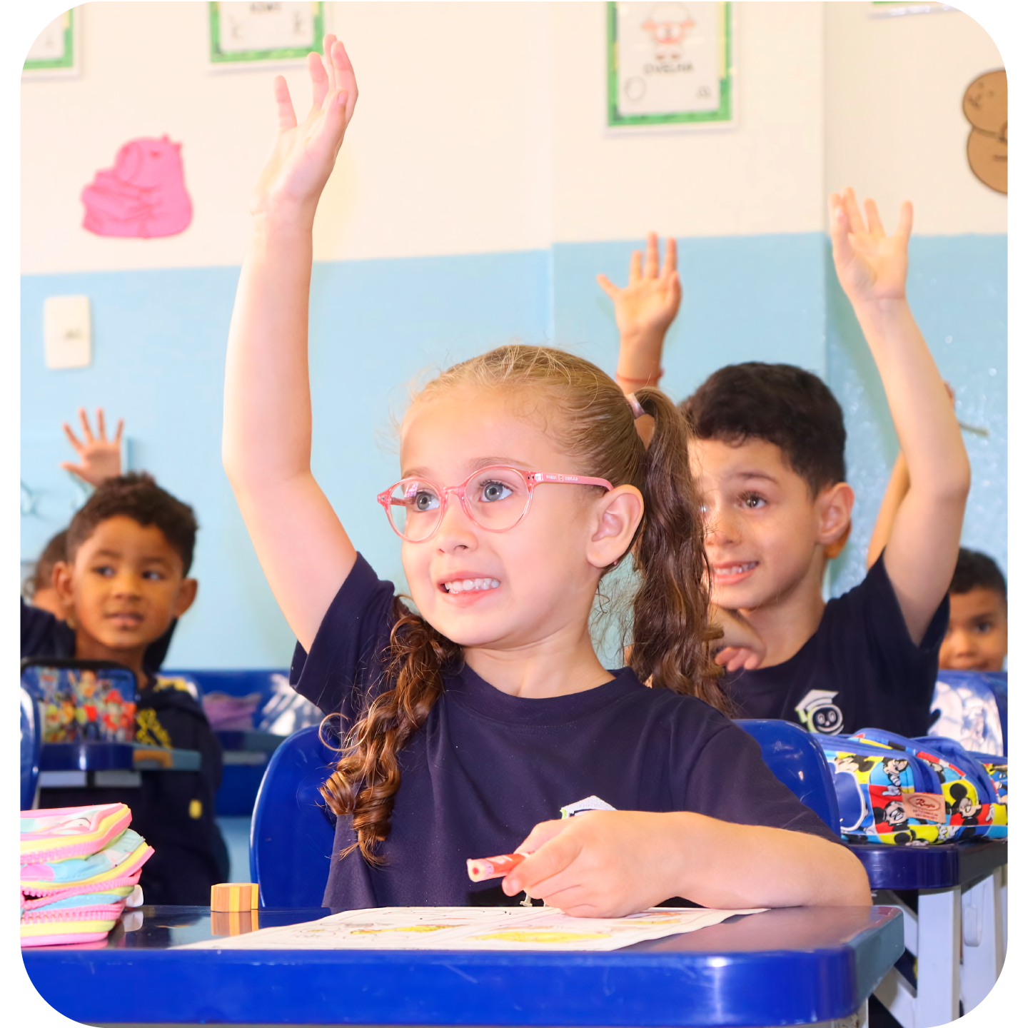 Crianças da Educação Infantil levantando a mão em sala de aula